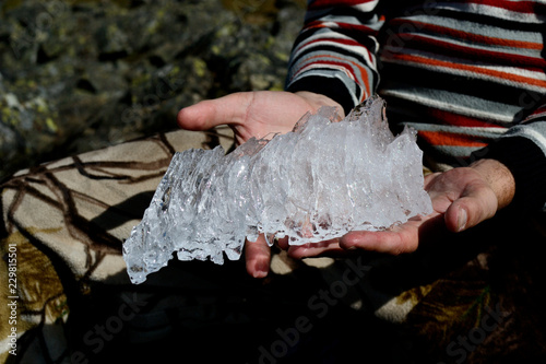 Beautiful piece of  crystalline ice in man's hands on the top of Konzhakovskiy Kamen mountain in summer photo