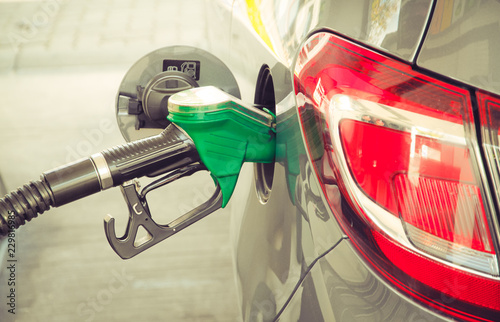 Car refueling at the petrol station. Concept photo for use of fuels (gasoline, diesel, ethanol) in combustion engines, air pollution and environmental and occupational health, oil price. Color toned.
