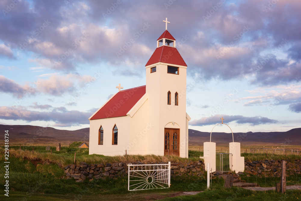 Small church against a beautiful cloudy sky background, icelandic landscape in sunset light. The evangelical lutheran church, main denomination in Iceland