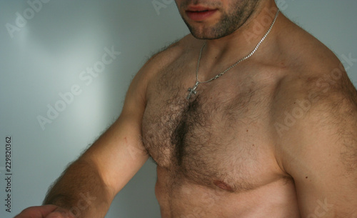 Muscled man presents his muscles. The athletic guy shows his chest and stomach.