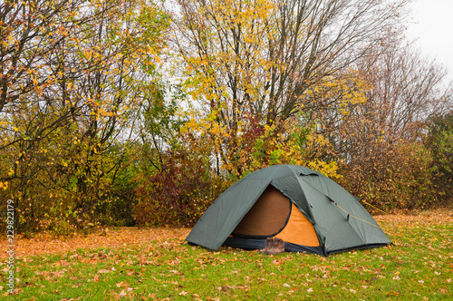  Tourist tent on the grass near the autumn forest