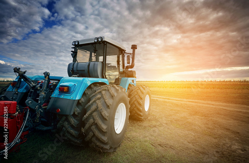 Fototapeta Naklejka Na Ścianę i Meble -  Tractor working in the field in the background of the sunset