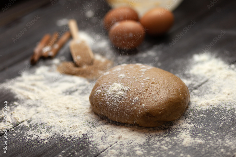 The process of preparing dough for Christmas cookies with cinnamon, ginger and sugar. On a dark brown background sprinkle with flour. Ingredients for cookies. New year's magic. With the blur The process of preparing dough for Christmas cookies with cinnamon, ginger and sugar. On a dark brown background sprinkle with flour. Ingredients for cookies. New year's magic. With the blur