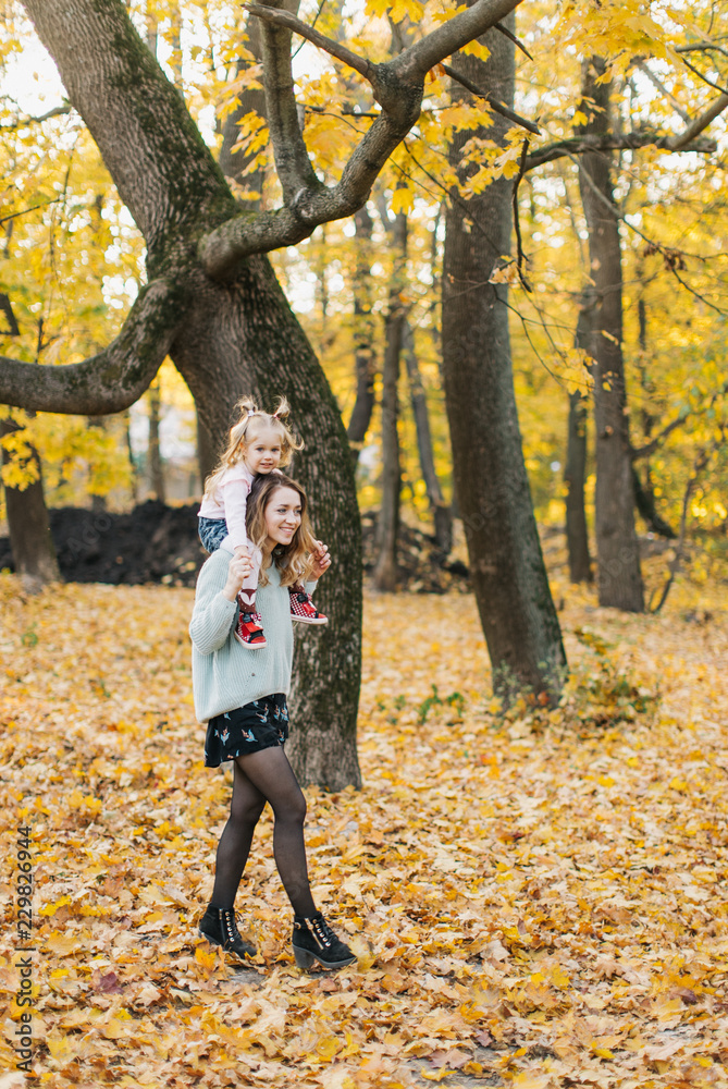 young mother with daughter are walking in the park in the golden autumn young mother with daughter are walking in the park in the golden autumn