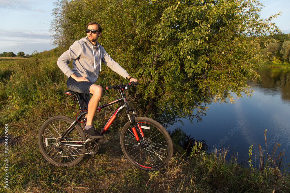 Young man on bicycle, bike in nature, summer autumn landscape