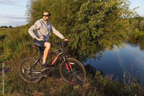 Young man on bicycle, bike in nature, summer autumn landscape