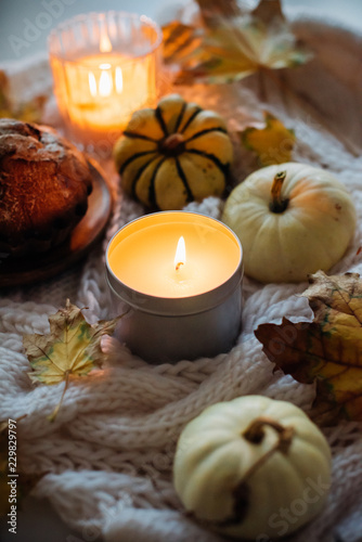 Burning candle in jar  autumn leaves and small decorative pumpki