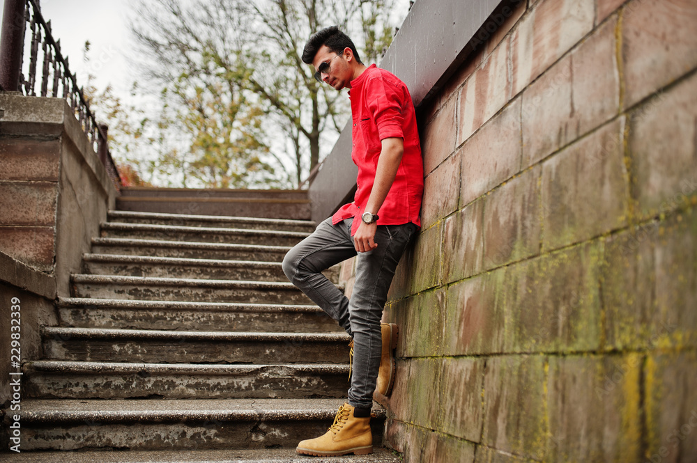 Indian man at red shirt and sunglasses posed outdoor. Indian man at red shirt and sunglasses posed outdoor.