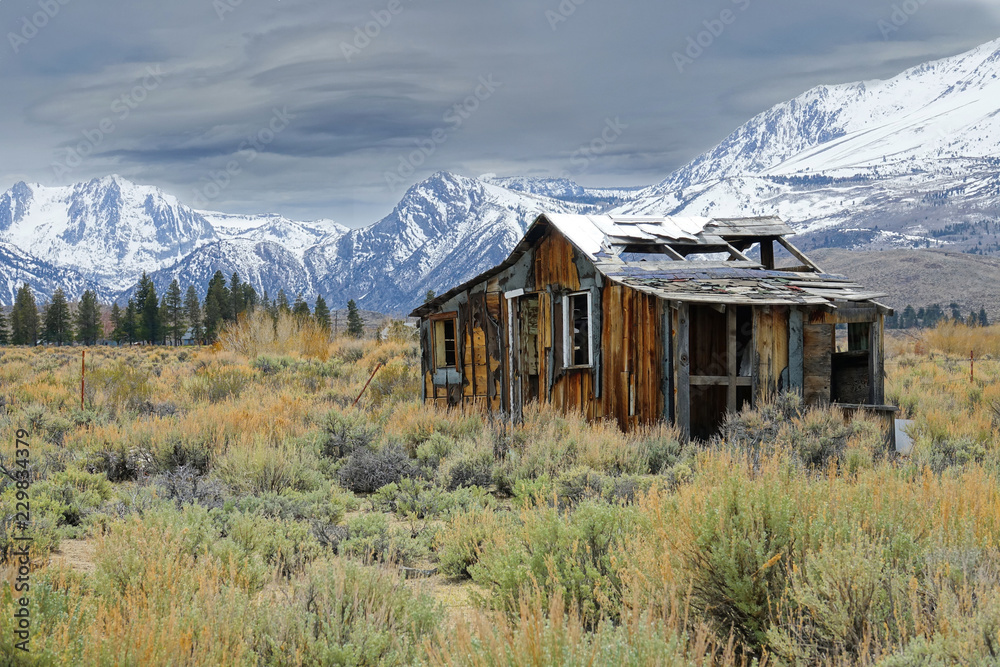 Lonely wooden cabin decaying in the rugged wilderness under the snowy mountains. Lonely wooden cabin decaying in the rugged wilderness under the snowy mountains.