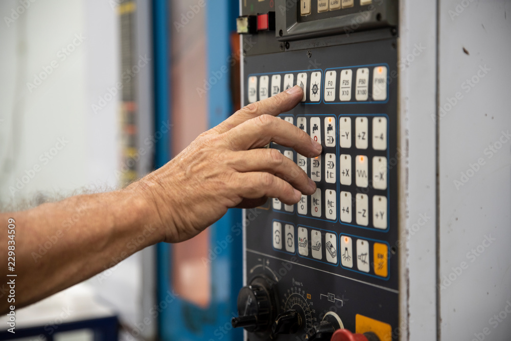 An employee presses the button on the control panel of CNC An employee presses the button on the control panel of CNC