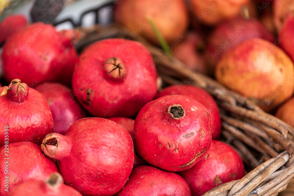 Closeup of fresh ripe, pink or red pomegranate round fruit, skin, whole in street farmer's market display bakset in Italy during summer, colorful vibrant Closeup of fresh ripe, pink or red pomegranate round fruit, skin, whole in street farmer's market display bakset in Italy during summer, colorful vibrant