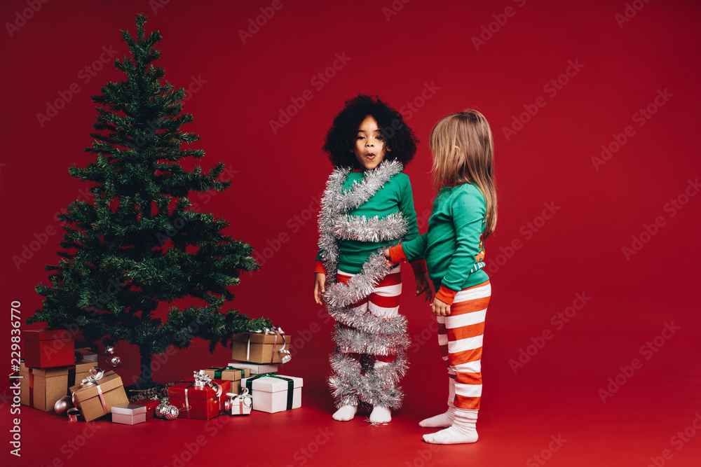 Kids having fun standing beside a christmas tree Kids having fun standing beside a christmas tree