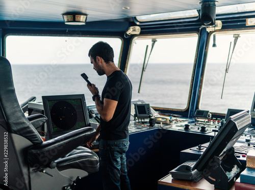 Marine navigational officer is reporting by VHF radio during navigation watch. Bridge GMDSS watch