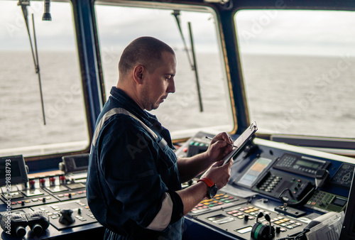 Marine navigational officer or chief mate on navigation watch on ship or vessel. He fills up checklist. Ship routine paperwork