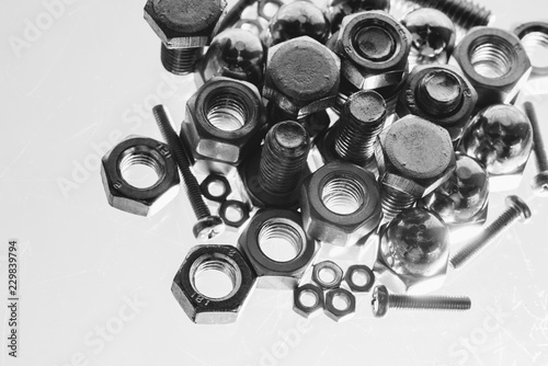 Art monochrome background from bolts and nuts close up in blue backlight. Macro photography of handful of fasteners. Copy space.
