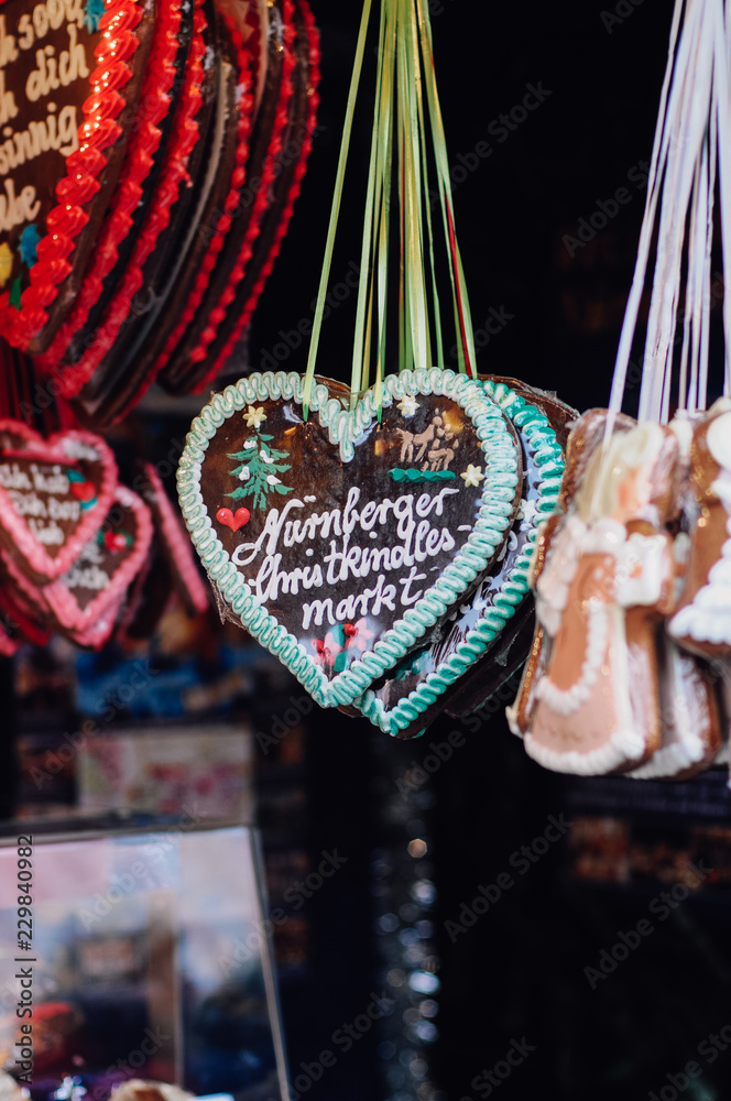 Traditional German Gingerbread heart, so called Lebkuchenkerz, a baked cookie with sugar icing, hanging at stall at Nuremberg Christmas market sold as gift for loved ones or souvenir