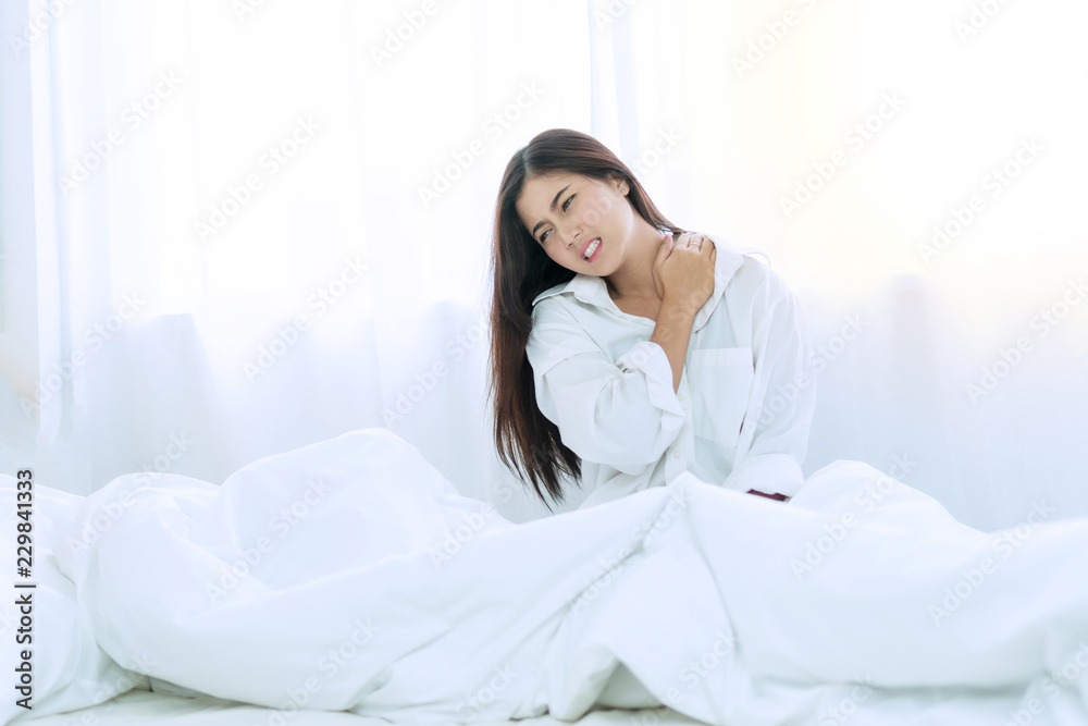 Healthy physical concept. Attractive young woman wake up in the morning on white bed with spine shoulder painful. She hands caught with her neck suffering. Have copy space. Healthy physical concept. Attractive young woman wake up in the morning on white bed with spine shoulder painful. She hands caught with her neck suffering. Have copy space.