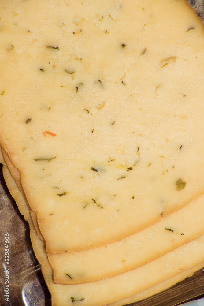 Slices of yellow cheese with herbs and spices Slices of yellow cheese with herbs and spices