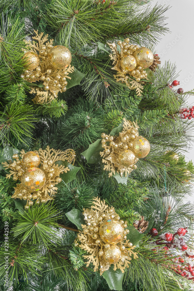 Close-up of Christmas tree in green colors and golden ornaments on white background
