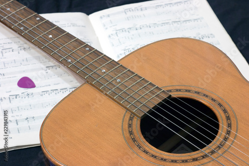 acoustic guitar on the background of a music book with notes and pick