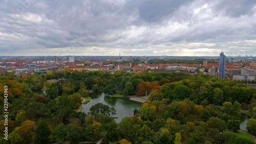 Aerial shot of a beautiful park with a cityscape and then going down in front of a windmill. 4k photo