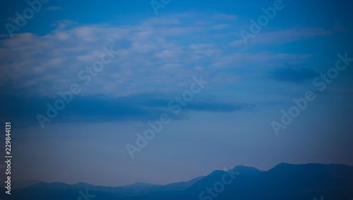 vivid mountain silhouette horizon line scenery nature landscape in evening twilight time and soft blue fog everywhere, copy space wallpaper