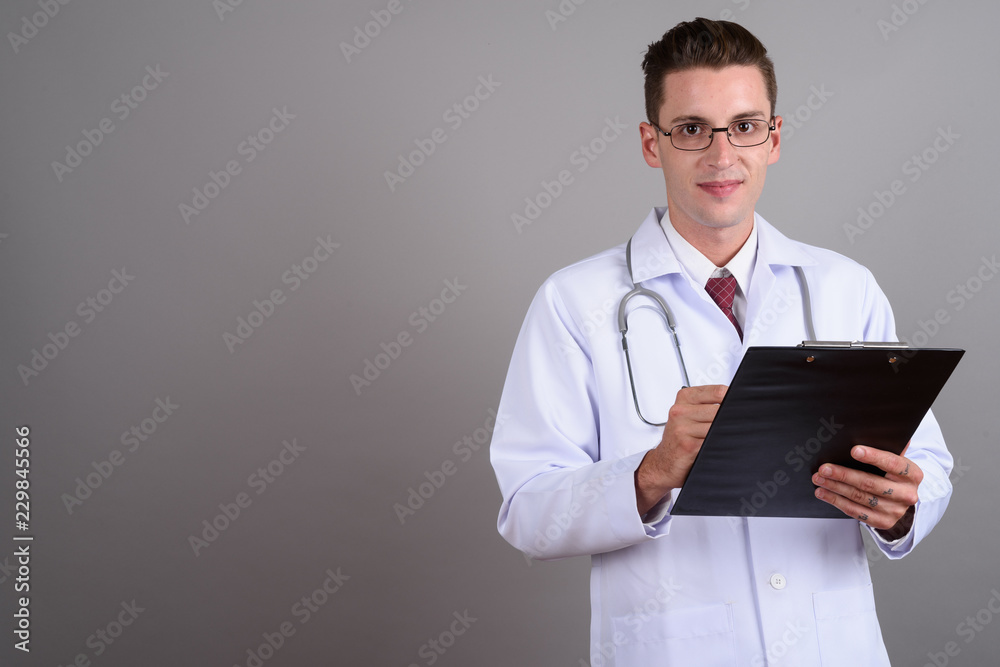 Portrait of young handsome man doctor holding clipboard Portrait of young handsome man doctor holding clipboard