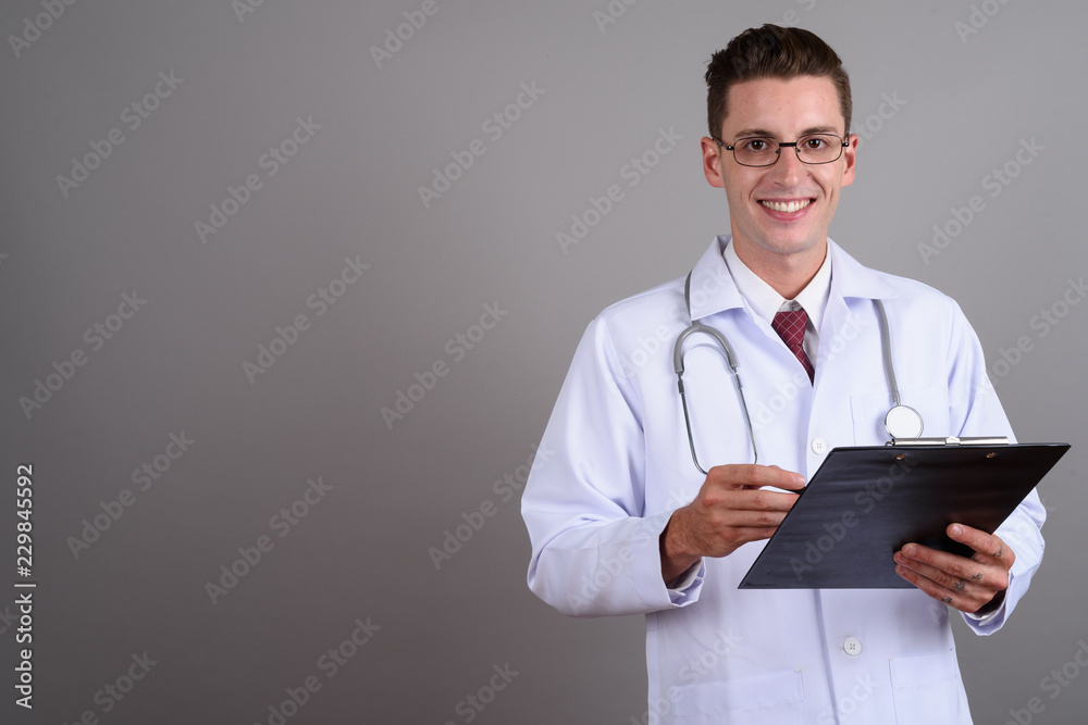 Portrait of young handsome man doctor holding clipboard while smiling Portrait of young handsome man doctor holding clipboard while smiling