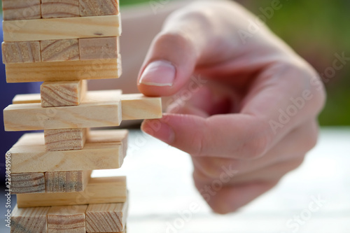Closeup of asian man's hand playing wood blocks stack game ,Planning, risk and strategy of project management in business background concept.