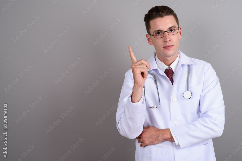 Young handsome man doctor pointing finger up Young handsome man doctor pointing finger up
