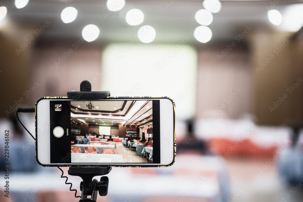 Blurred of live smartphone Video camera or camcorder operator working for  record couple speaker or Presenterson stage in conference and convention  hall blur light bokeh background Stock Photo | Adobe Stock