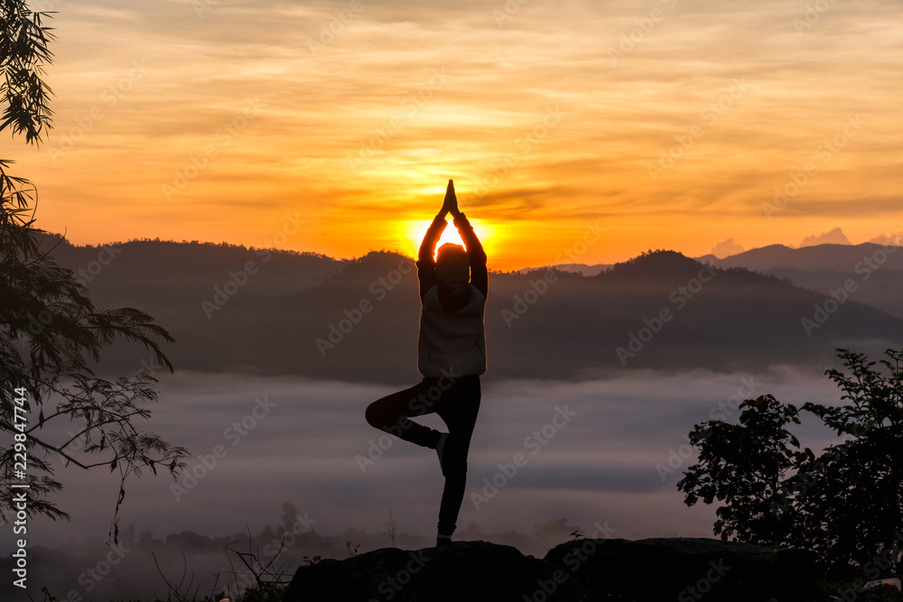 Silhouette of girl doing yoga at sunrise with foggy