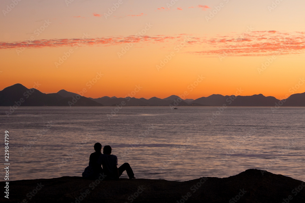 Romantic couple silhouette at sunrise by the sea