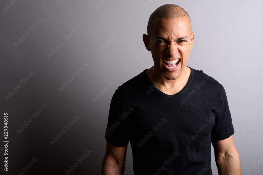 Handsome bald man looking angrily at camera while screaming