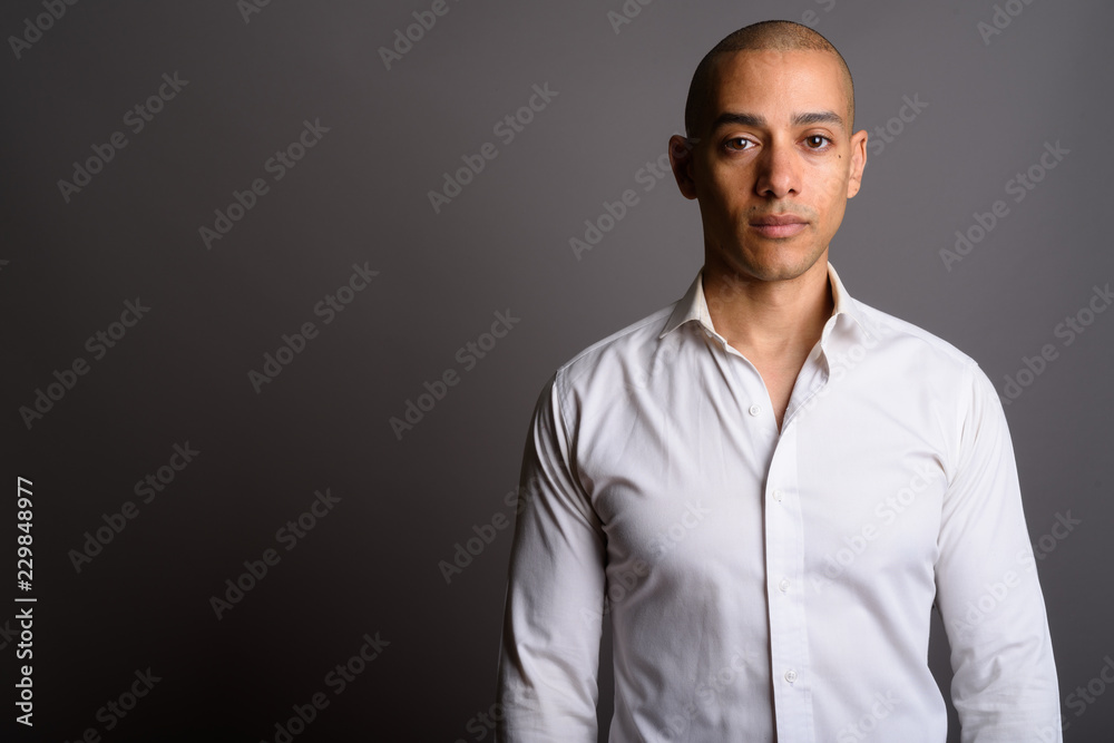 Handsome bald businessman looking at camera against gray background Handsome bald businessman looking at camera against gray background