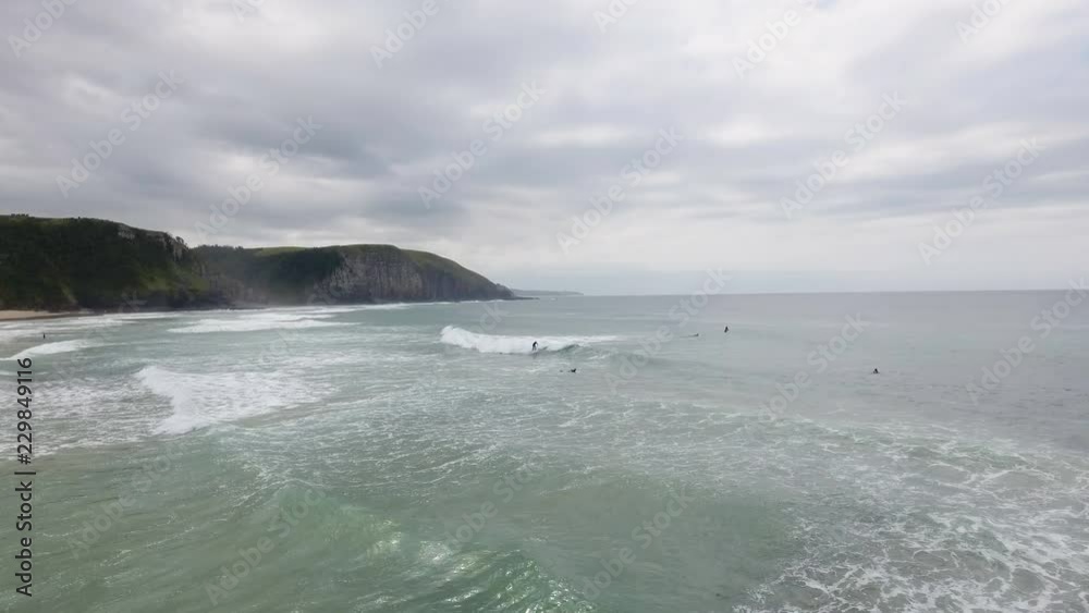 Cinematic flying of surfers surfing along coast of East London South Africa aerial Cinematic flying of surfers surfing along coast of East London South Africa aerial