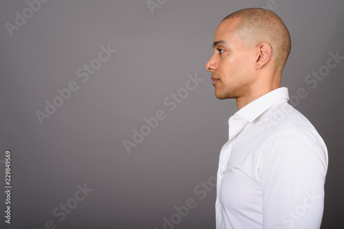 Profile view of handsome bald businessman against gray background