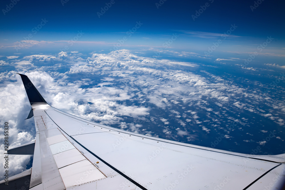 High altitude. Sky, clouds and atmosphere seen from an airplane. Ocean, white clouds, airplane wing and the earth atmosphere.
