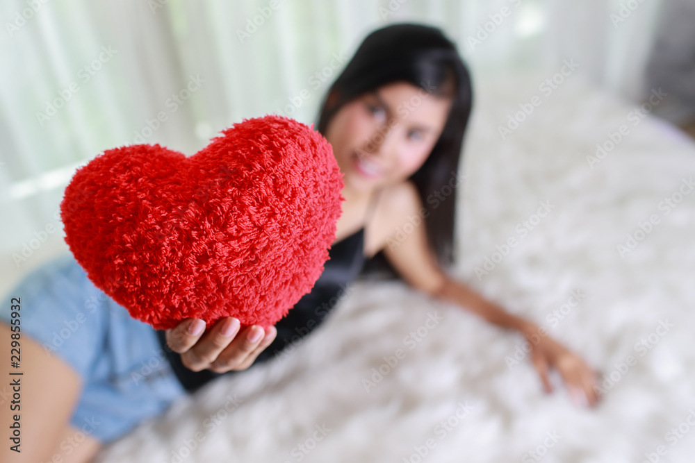 beautiful and sexywoman lie down on bed with red heart in her hands beautiful and sexywoman lie down on bed with red heart in her hands