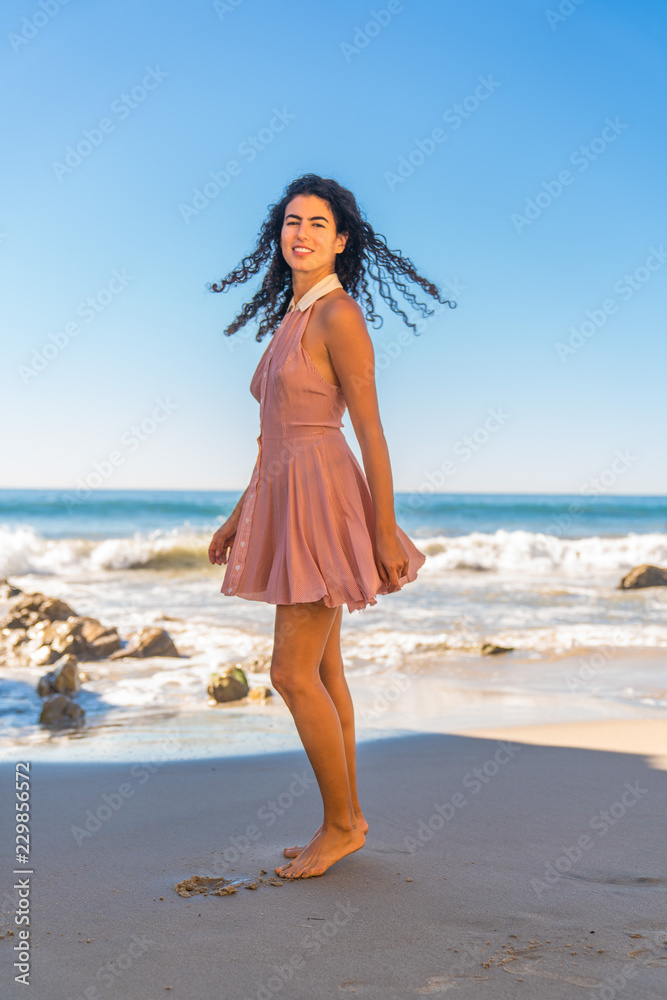 Portrait of latino woman with curly hair dancing at beach