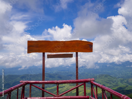 Blank of wooden billboard for advertisement with moutains and sky cloudy background. © meeboonstudio
