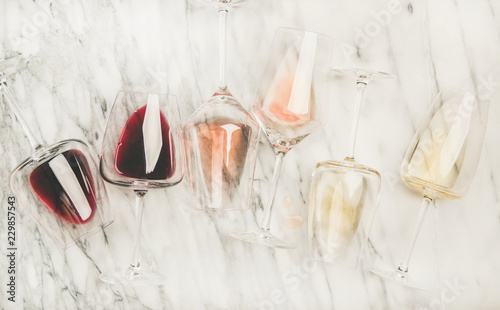 Flat-lay of red, rose and white wine in glasses and corkscrews over grey marble background, top view. Bojole nouveau, wine bar, winery, wine degustation concept photo