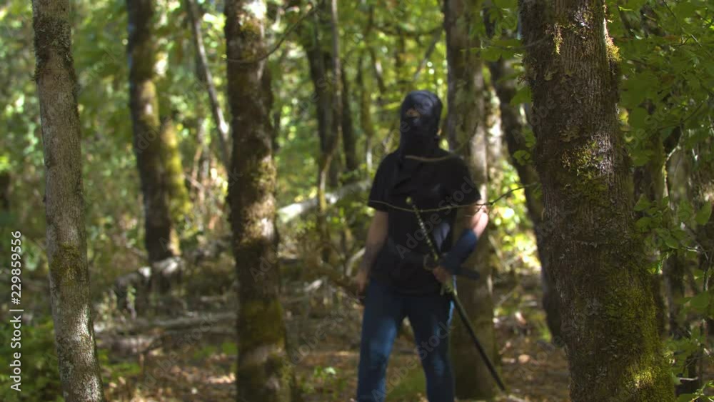 Girl in a Ninja Outfit Walking through the Trees in Slow Motion Girl in a Ninja Outfit Walking through the Trees in Slow Motion