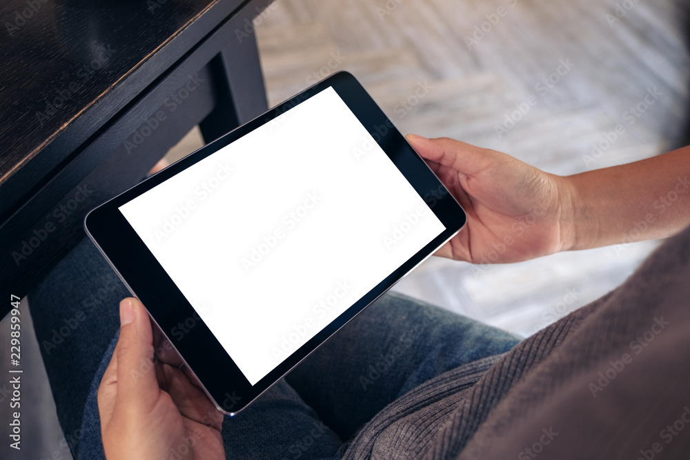 Mockup image of a woman sitting and holding black tablet pc with blank white desktop screen Mockup image of a woman sitting and holding black tablet pc with blank white desktop screen