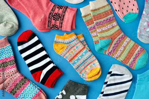 Colorful socks on blue background. View from above. Many different socks for everyone. Clothing in the form of socks on a bright blue background.