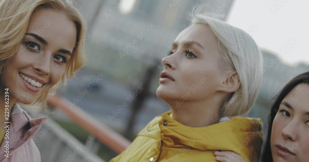 Portrait of three young multiracial women talking in street. Female models wearing jeans and long jacket coat. 4k video steadicam shot . Evening urban city outdoor style Portrait of three young multiracial women talking in street. Female models wearing jeans and long jacket coat. 4k video steadicam shot . Evening urban city outdoor style