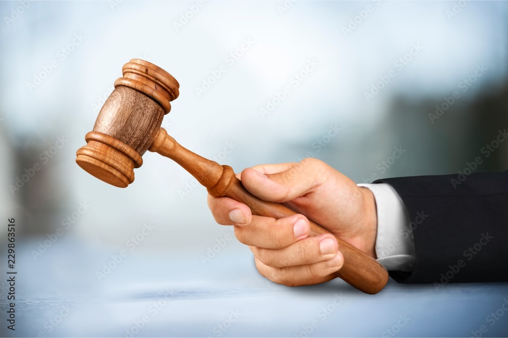 Male hand with wooden judge hammer, shelves Male hand with wooden judge hammer, shelves