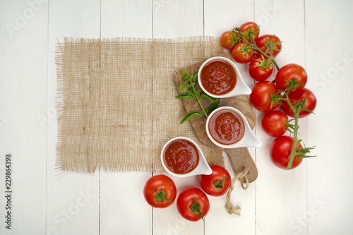 Tomato sauce.tomato ketchup.The recipe for ketchup. home made sauce ketchup in white plates, red tomatoes and burlap on a white wooden board background