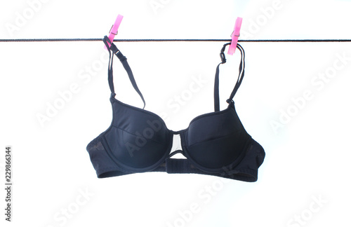 Black female bra hanging on a clothesline with buckles isolated on white background. photo