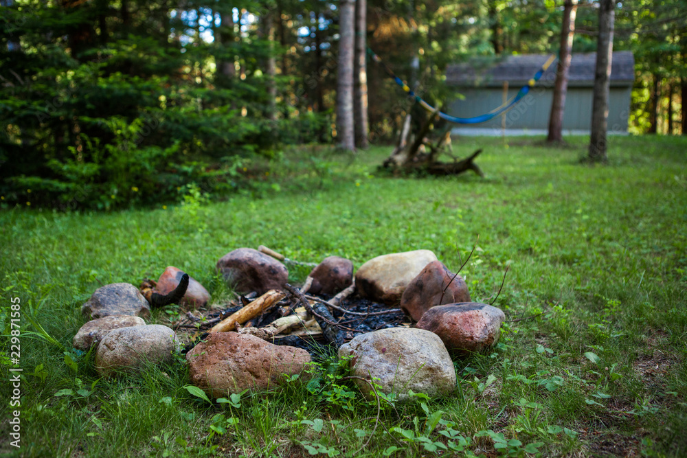 Campfire pit on green lawn with a hammock hanging in the background - 1/2 - Wide angle picture showing a big part of the backyard Campfire pit on green lawn with a hammock hanging in the background - 1/2 - Wide angle picture showing a big part of the backyard